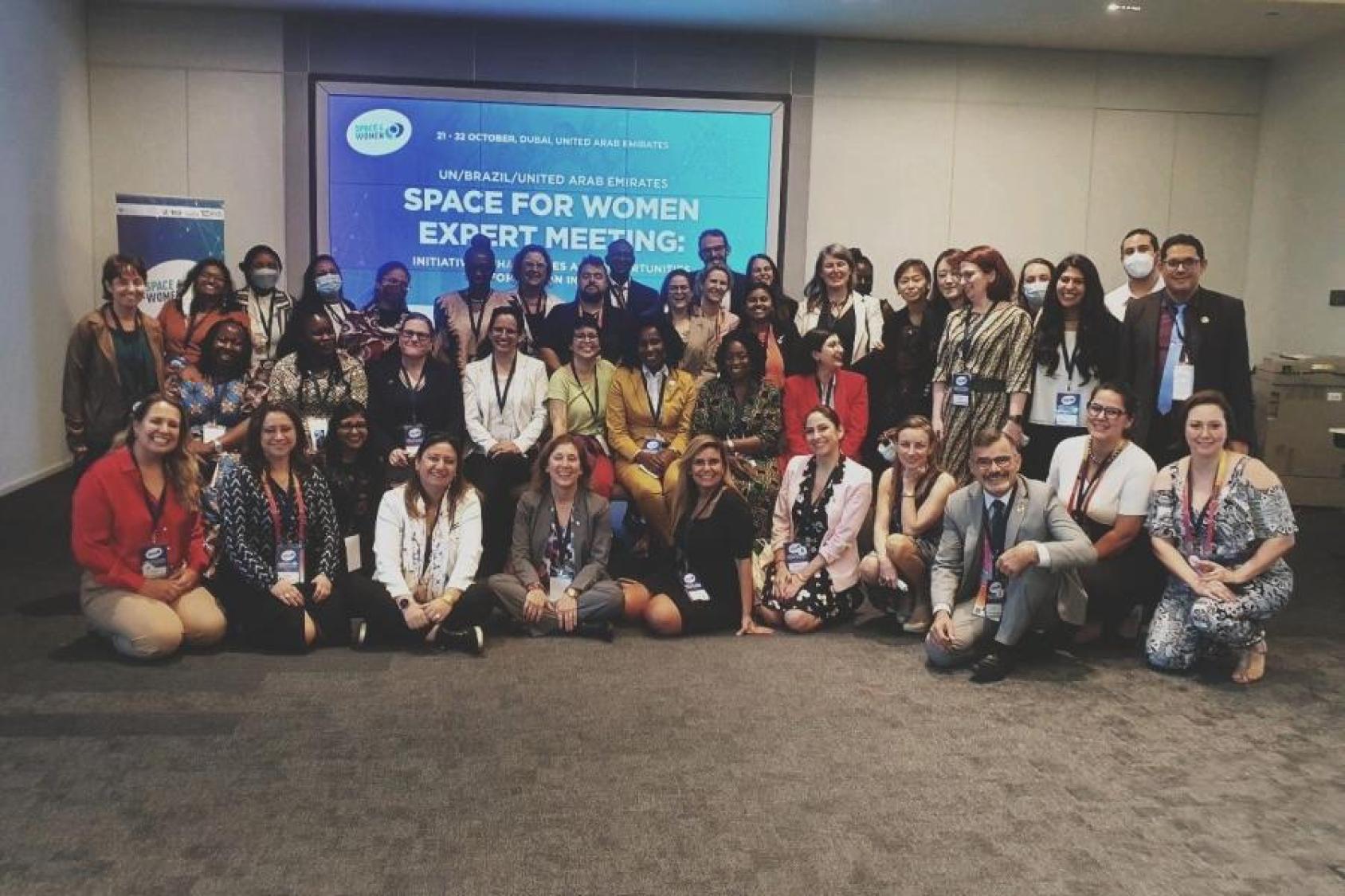 Group of women standing, some crouched in different coloured clothing at a meeting