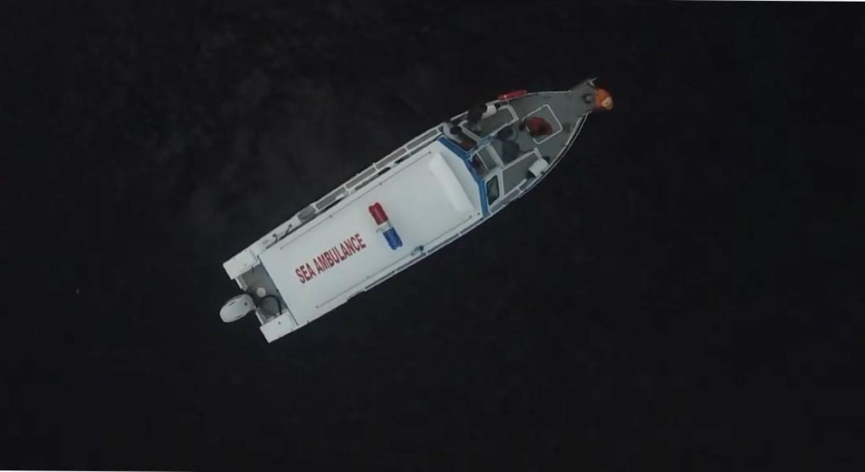 An aerial shot of a white boat with the letters "sea ambulance" on it