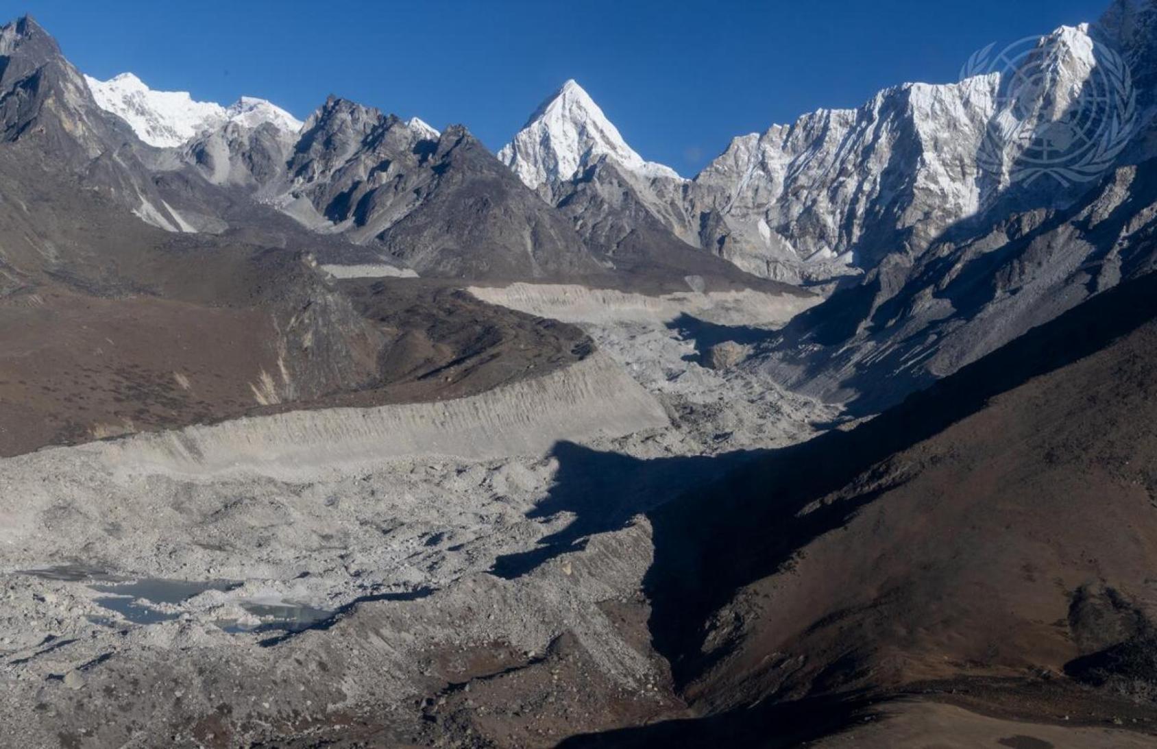 A wide angle shot of snow capped mountains and a stony pass through it in Nepal