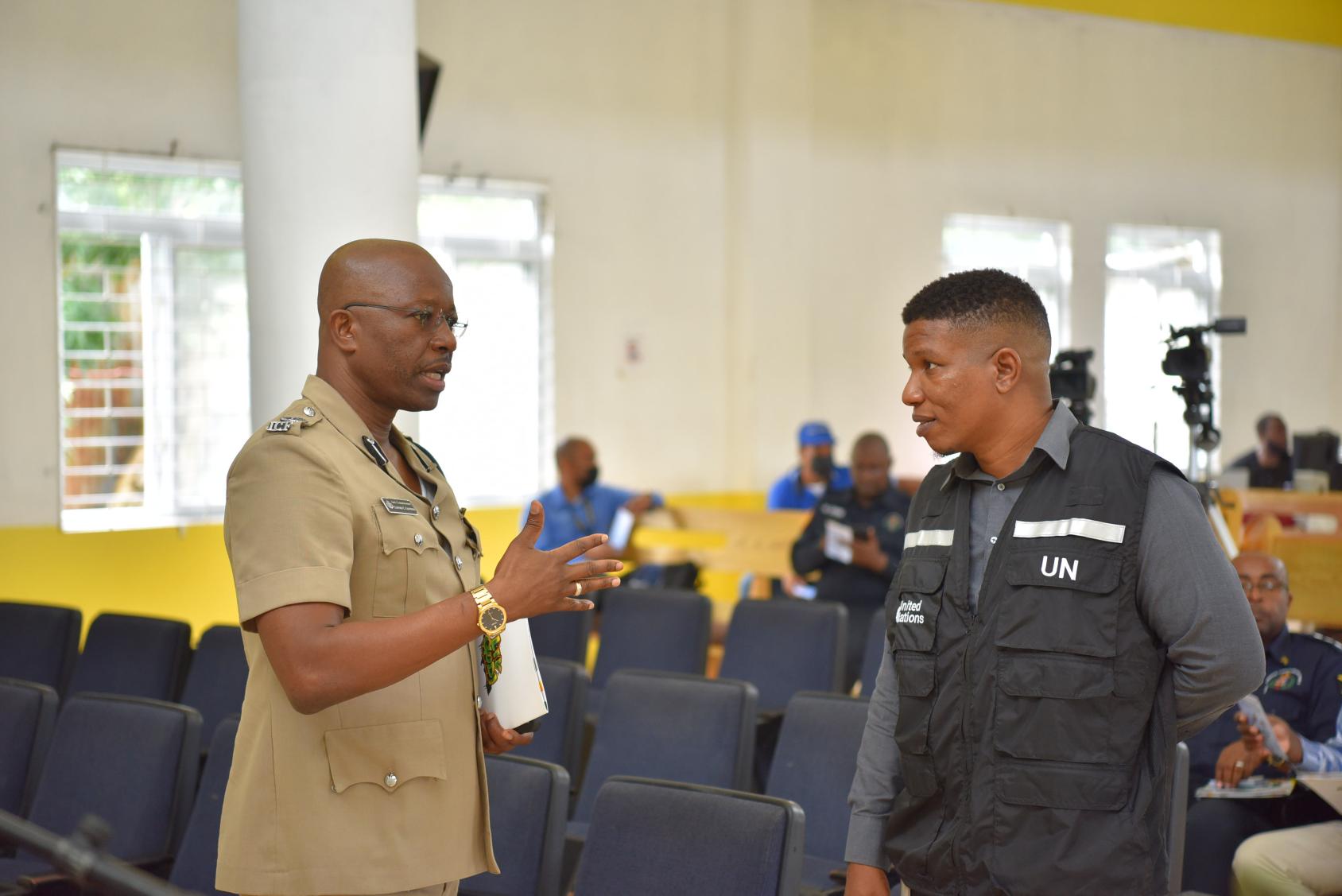 A man in a khakhi dress talks with another man dressed in a dark blue policeman's atire