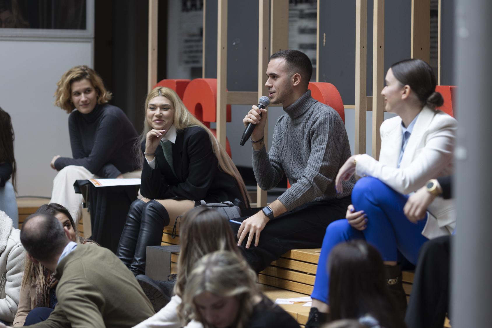 A man sits with a group of women and speaks -up 