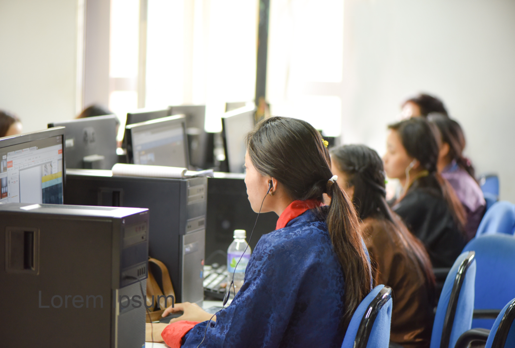 A line of schoolgirls sit at computer desks