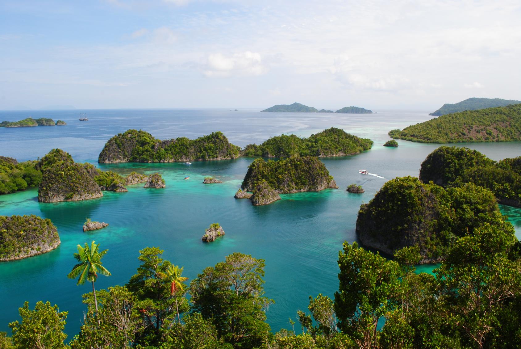 An aerial view of islands in Indonesia- lush and green against blue ocean waters