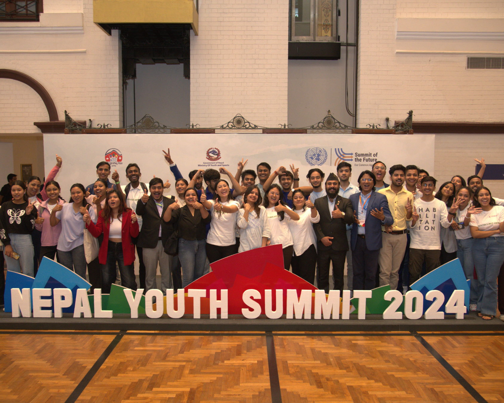 A group photo with many young people in front of a sign saying "Nepal youth summit 2024"