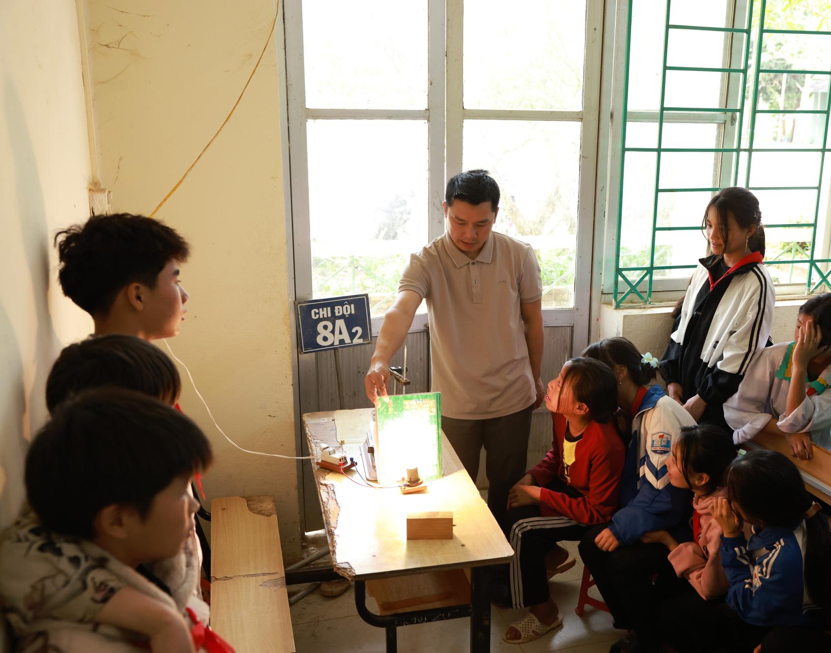 A group of students gather around a light bulb in a classroom