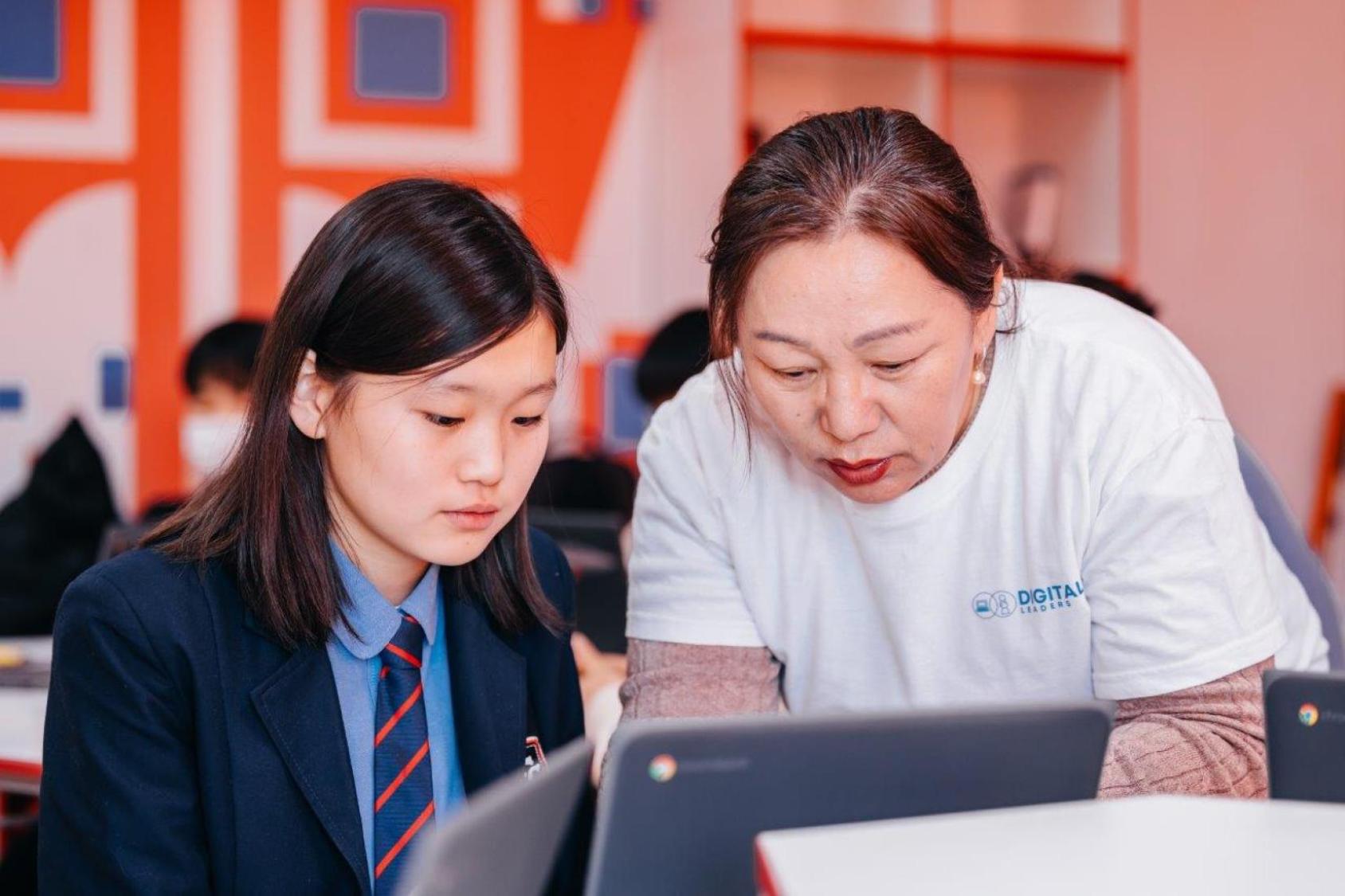 An instructor is teaching a student in front of a computer.