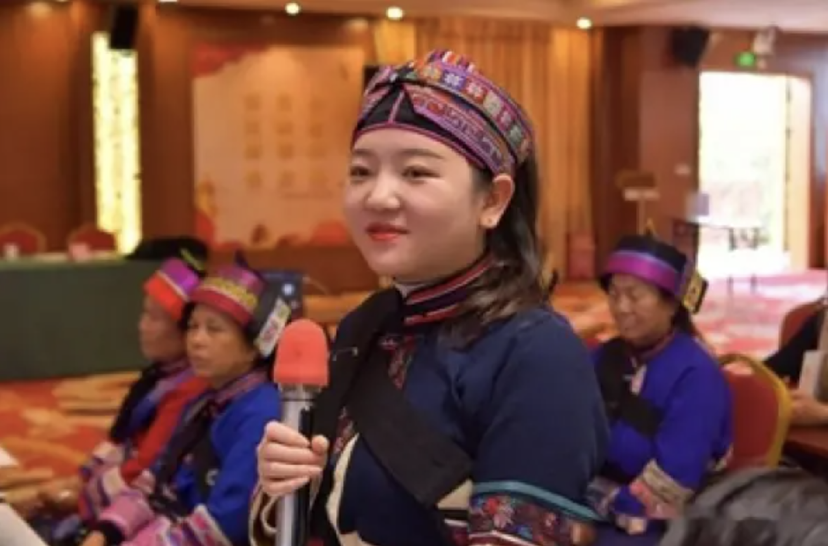 一位女性穿着傣族服装 手持话筒准备发言