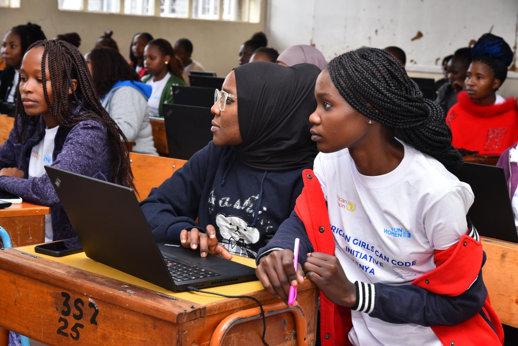 A group of girls in a classroom in Kenya with a computer open in front of them