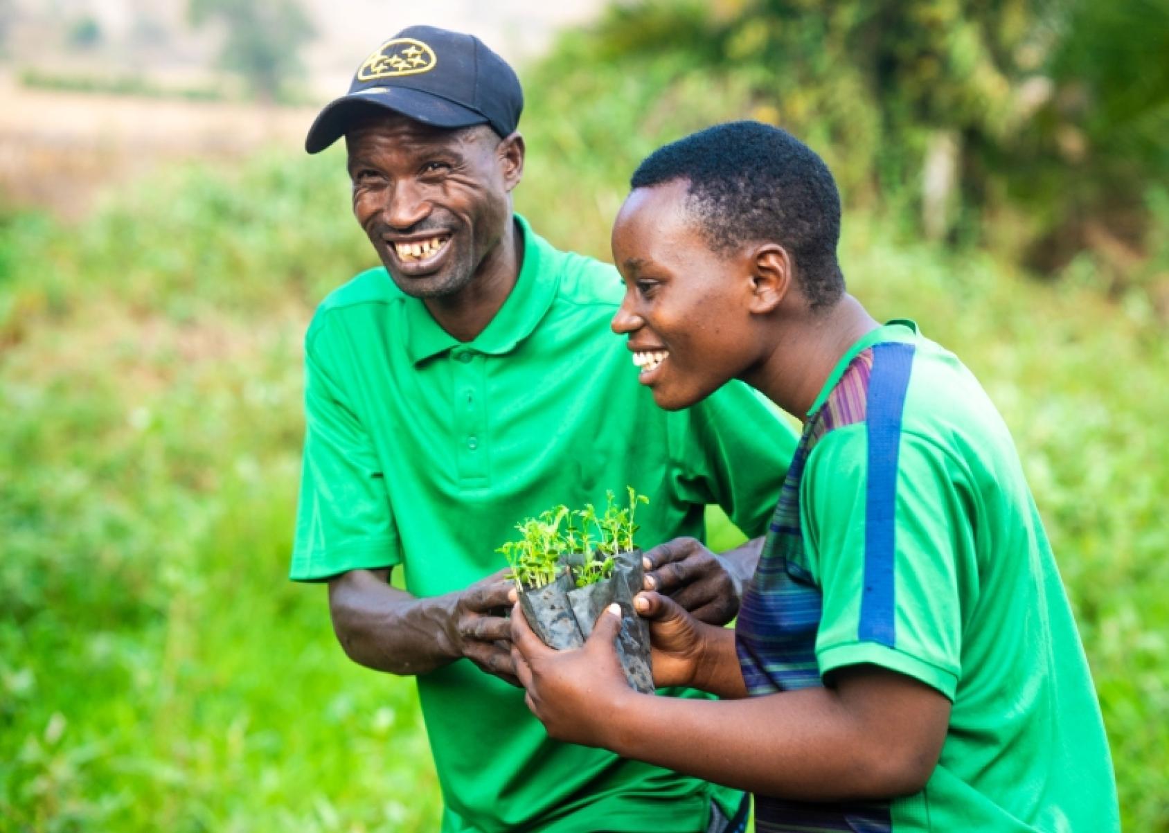 Два пчеловода держат саженцы деревьев