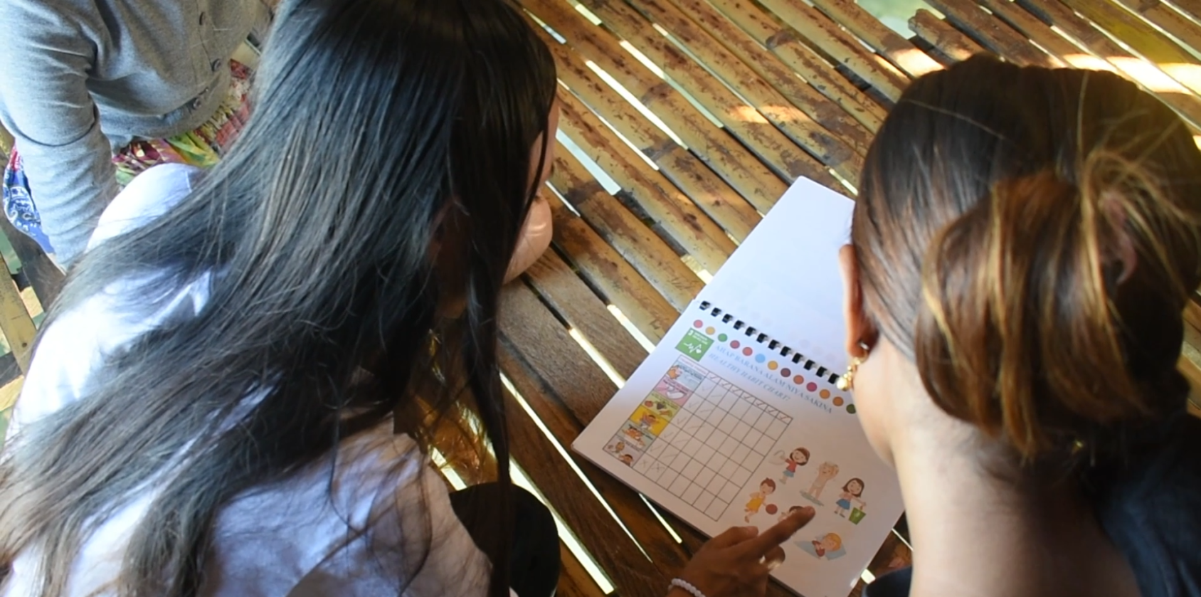 Two young women leaning over a book in a school