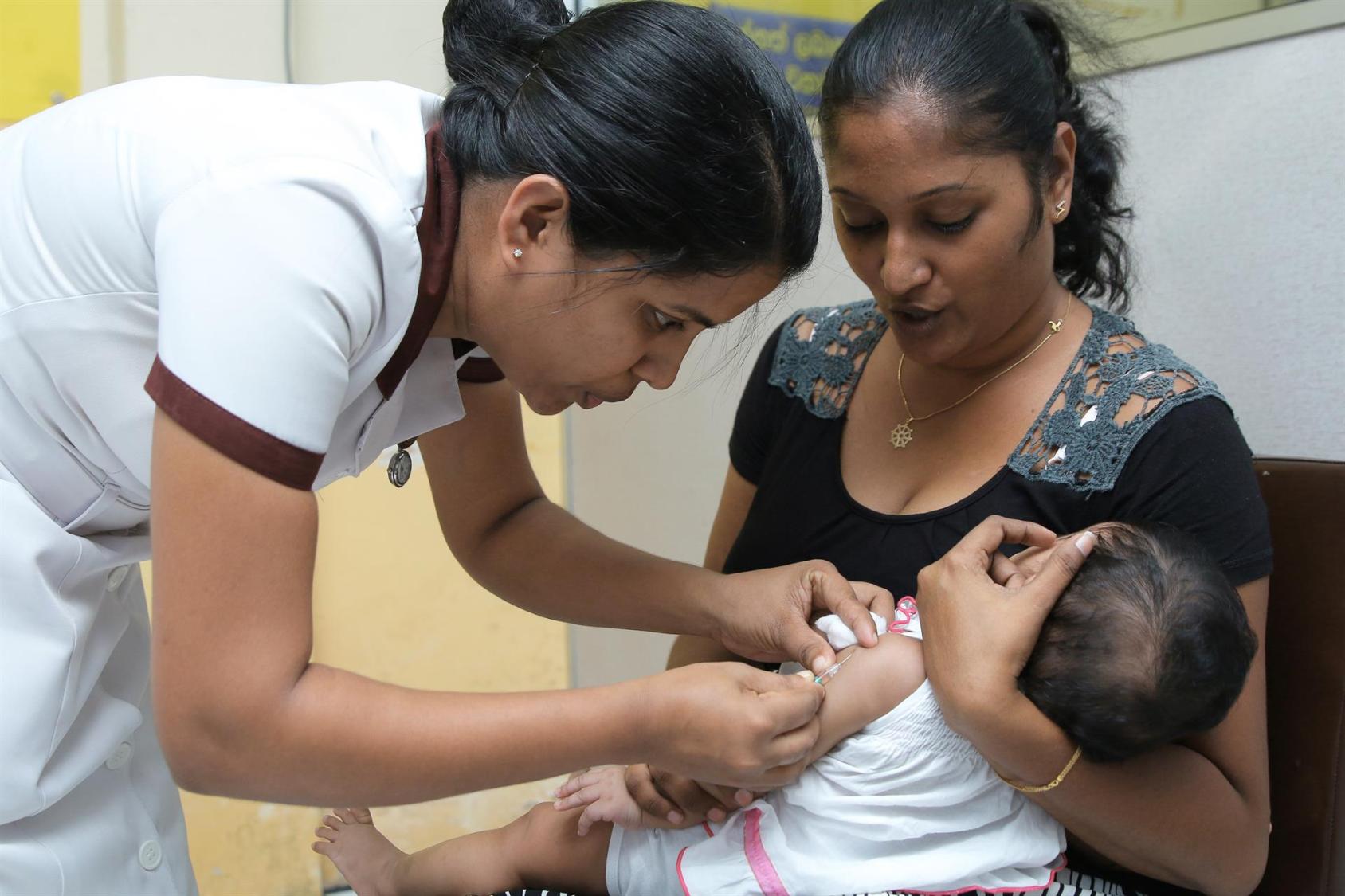 ممرضة في سريلانكا تُعطي لقاحًا لطفل صغير ضمن برنامج صحي وطني متماشي مع أهداف التنمية المستدامة.