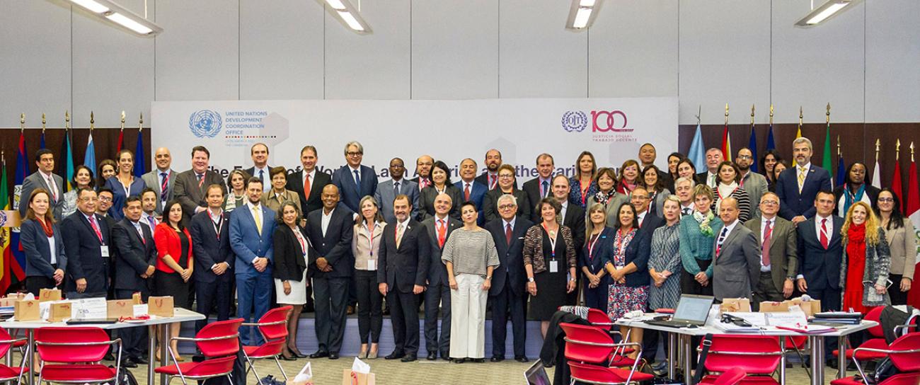 ممثلين عن مكتب التنسيق الإنمائي التابع للأمم المتحدة ومنظمة العمل الدولية يقفون أمام لافتة عليها شعاري المكتب والمنظمة.