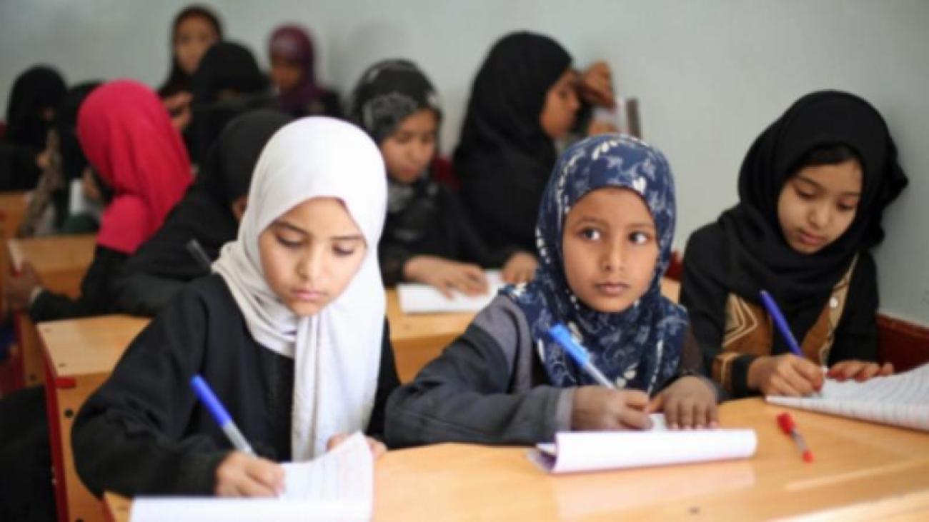 Tres niñas tomando notas en clase.