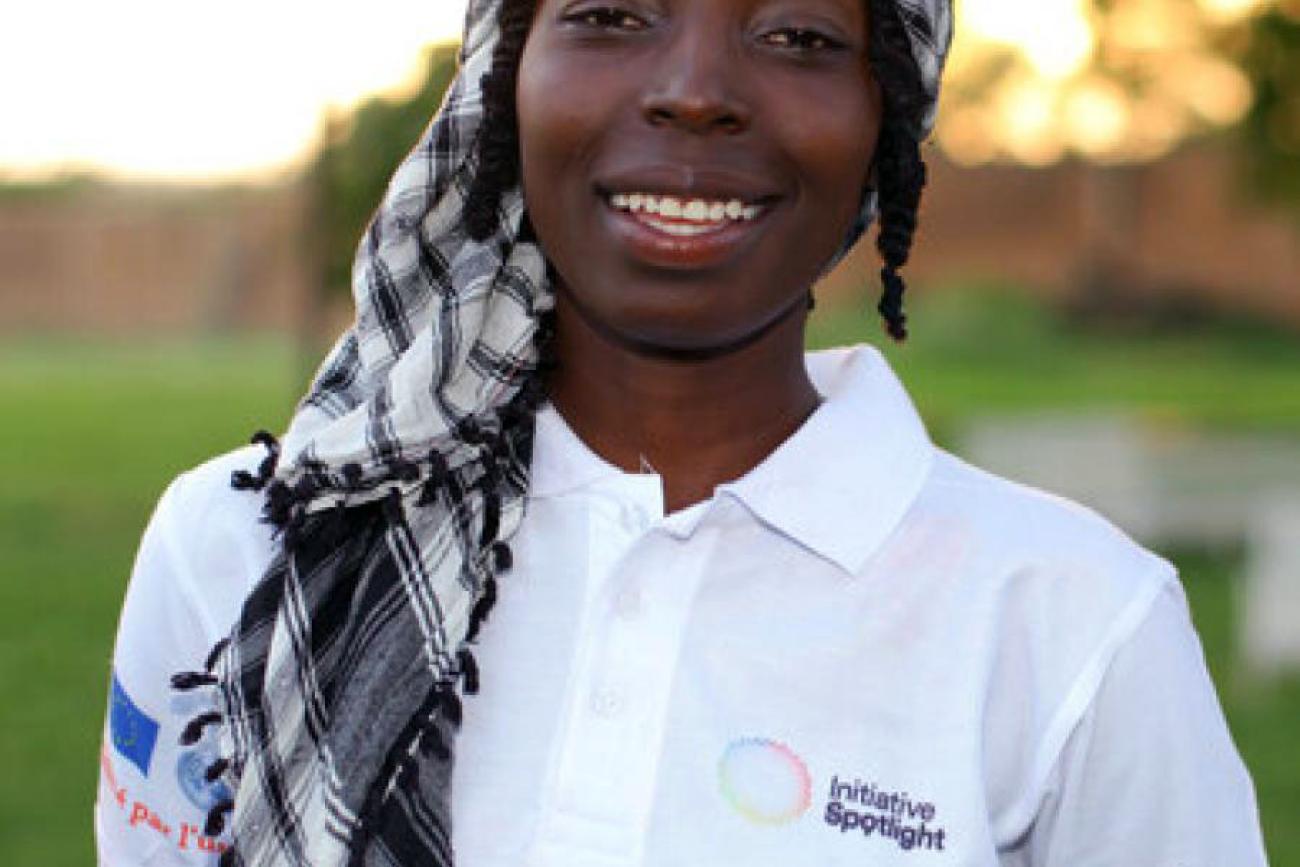 Photo de la poétesse Hama Daouda Fatouma portant un polo blanc de l’Initiative Spotlight et souriant à la caméra.