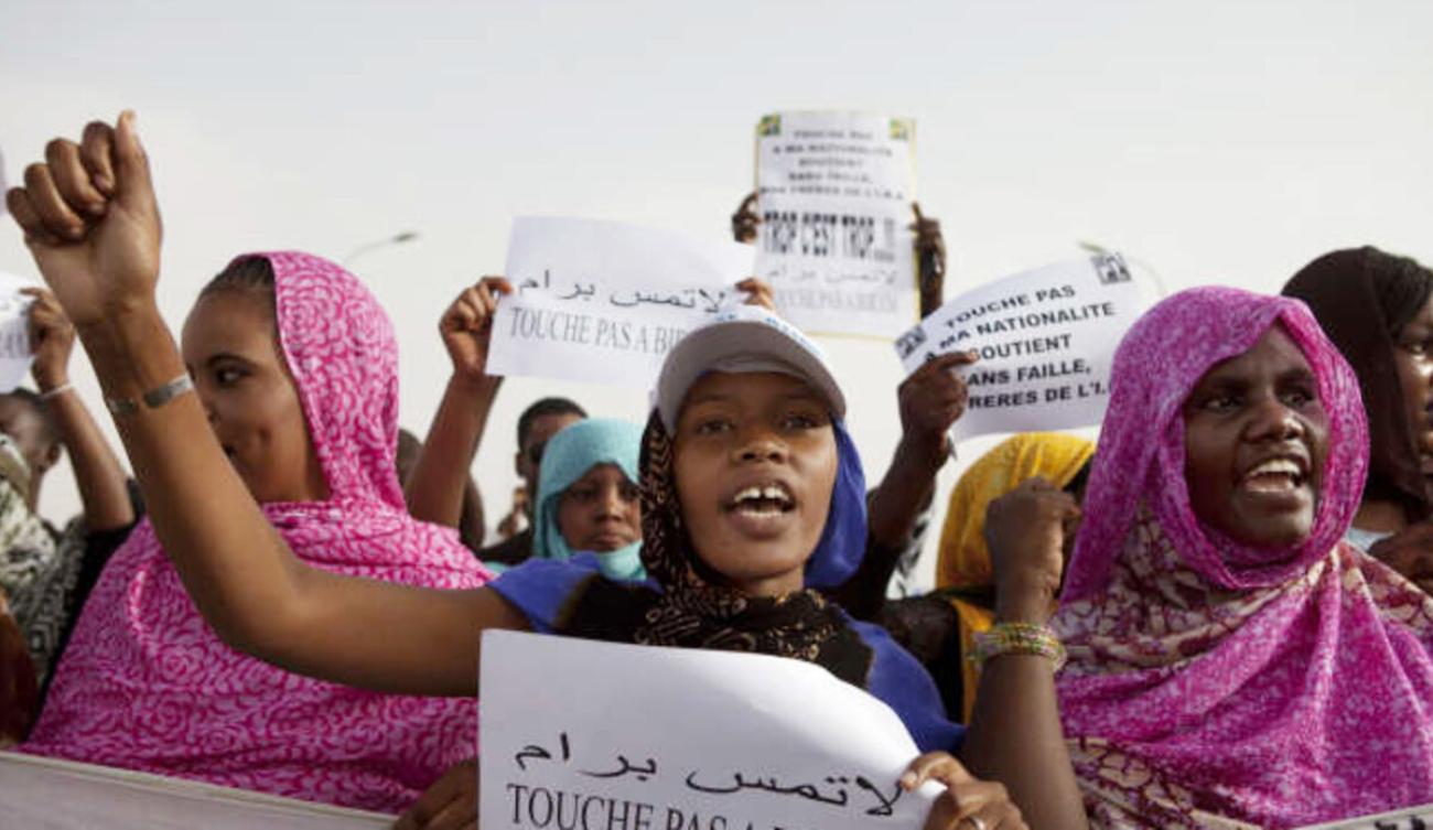 Des militantes antiesclavagistes manifestent à Nouakchott, en Mauritanie. Plusieurs d’entre marchent le poing levé, en brandissent des pancartes.