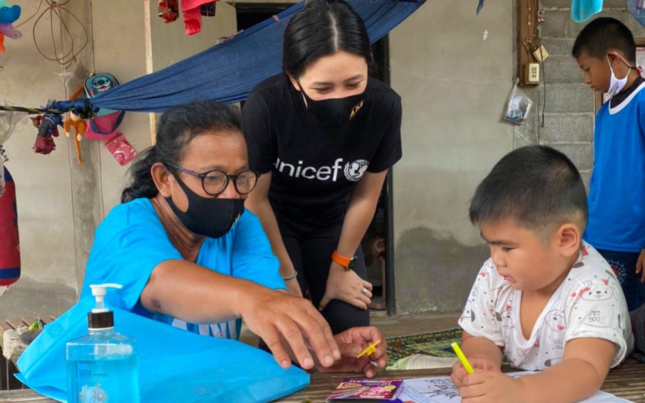 تتحدث المتطوعة في اليونيسف، راسا باتيكاسيمكول (في الوسط)، إلى صبي صغير في لقاء نادر وجهًا لوجه خلال الإغلاق الذي تسببت به جائحة كوفيد-19.