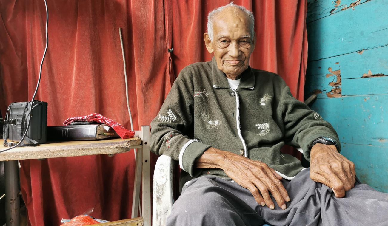 كانديلاريو يبتسم وهو جالس إلى جانب طاولة عليها معدات إلكترونية.