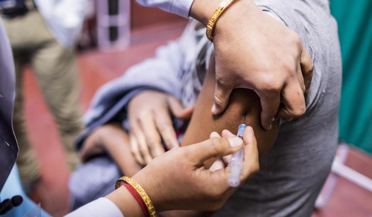 صورة مقربة لمقدم خدمات طبية تحقن ذراع شخص بلقاح كوفيد-19.