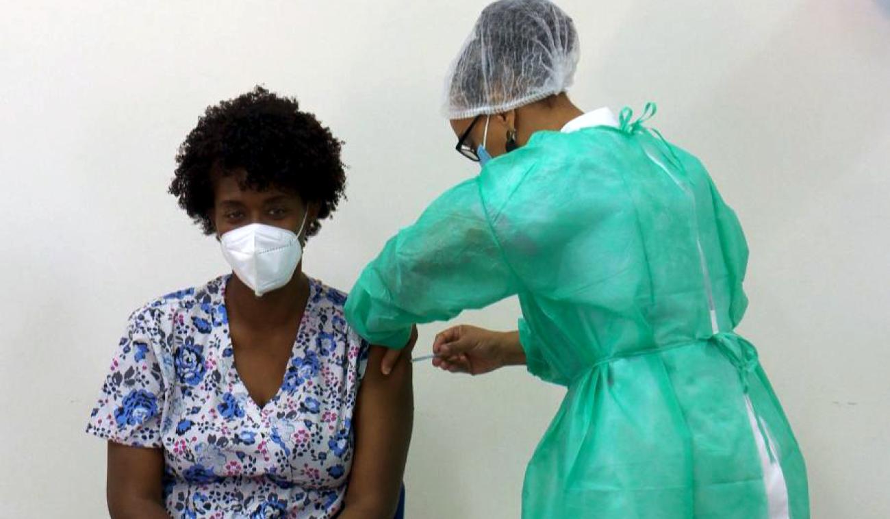 Ana Manuela, a health technician, sits patiently as she receives the COVID-19 vaccine.