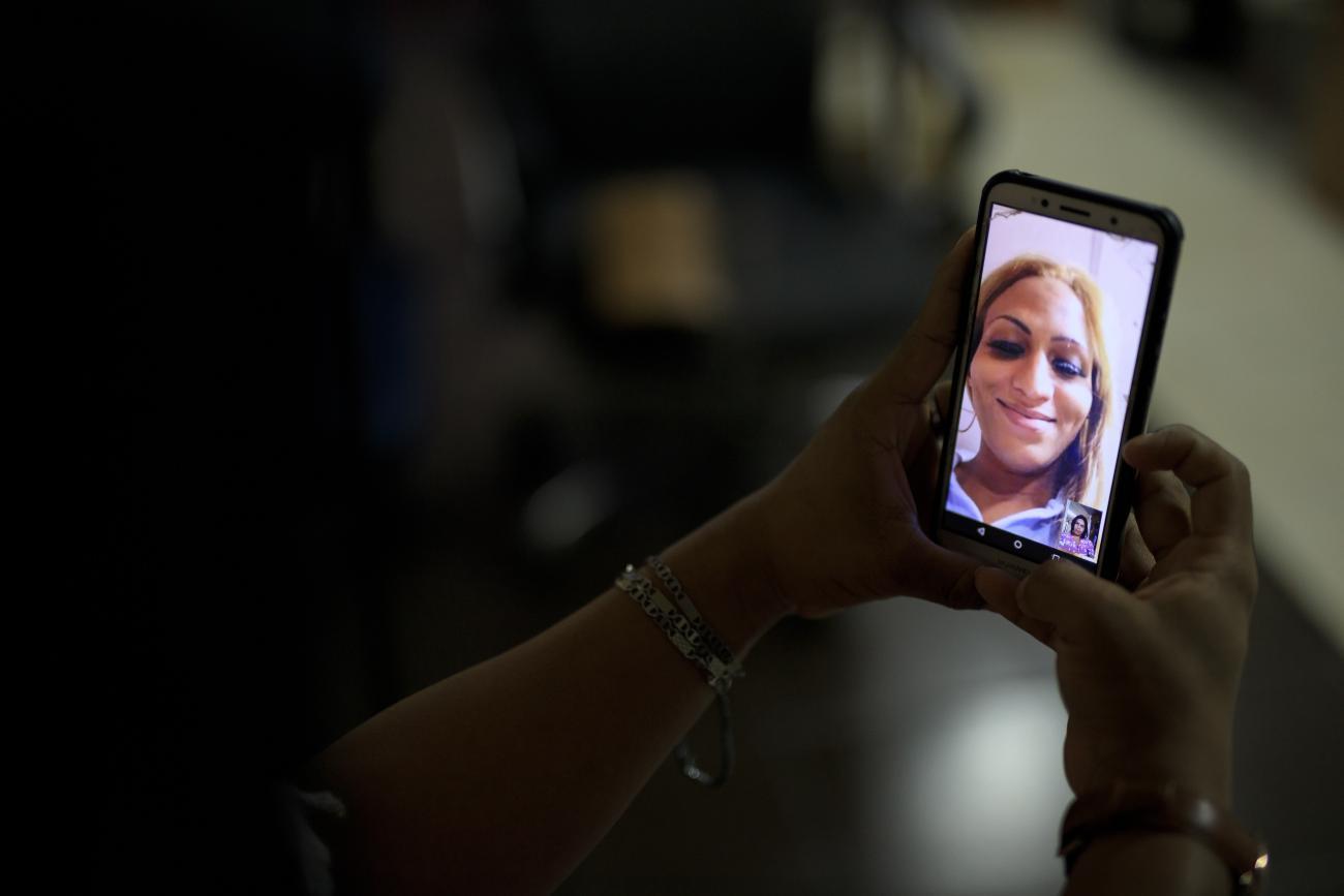 An image of a person's hand holding a cellphone with another person