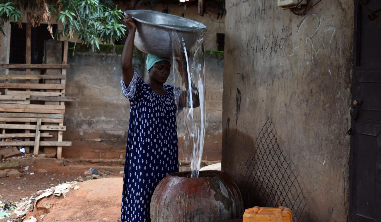 Adisa Abdul Rhaman pours water into her pot outside her home.