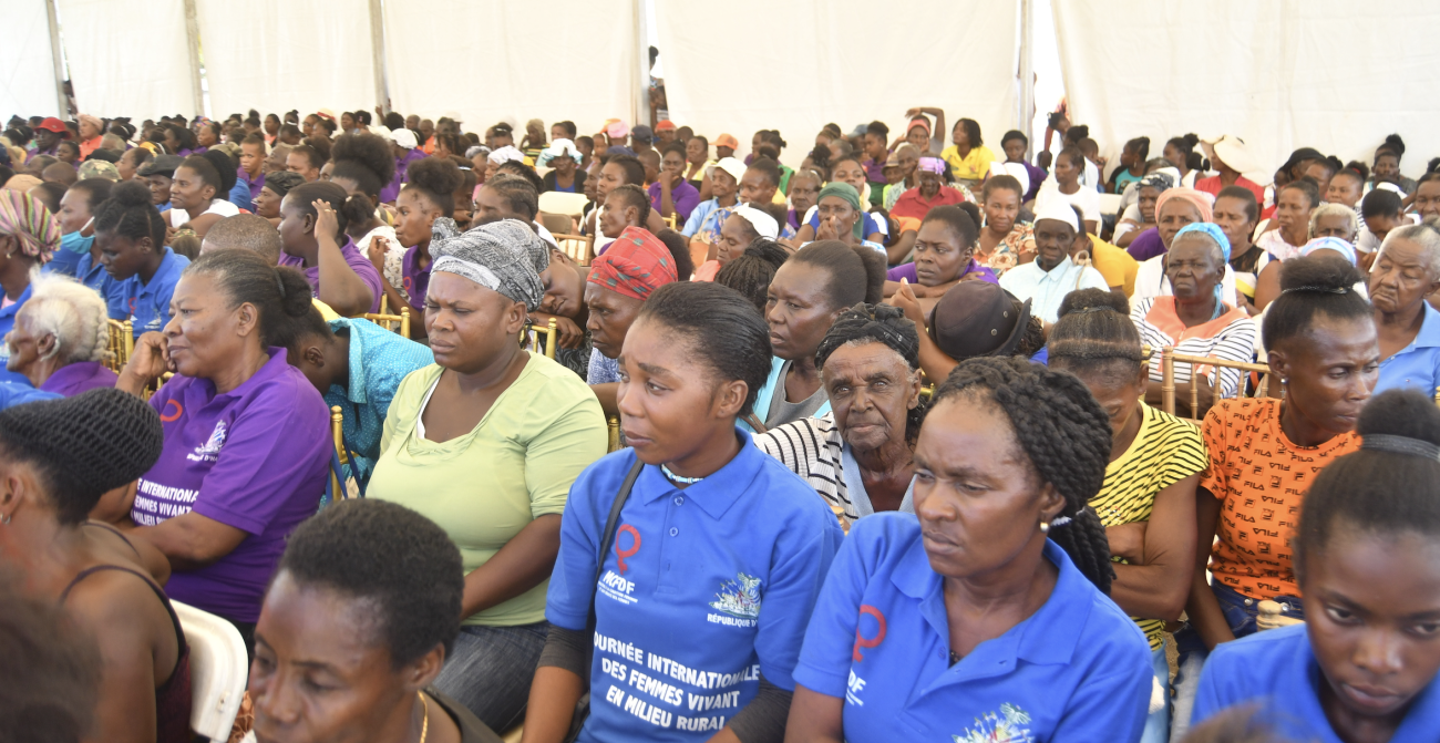 Un numeroso grupo de mujeres se sientan juntas en una gran tienda de campaña.