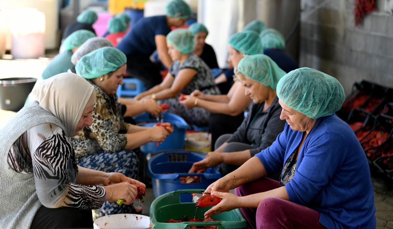 Women of Krusha/Kruša sit together on the floor as they make ajvar 