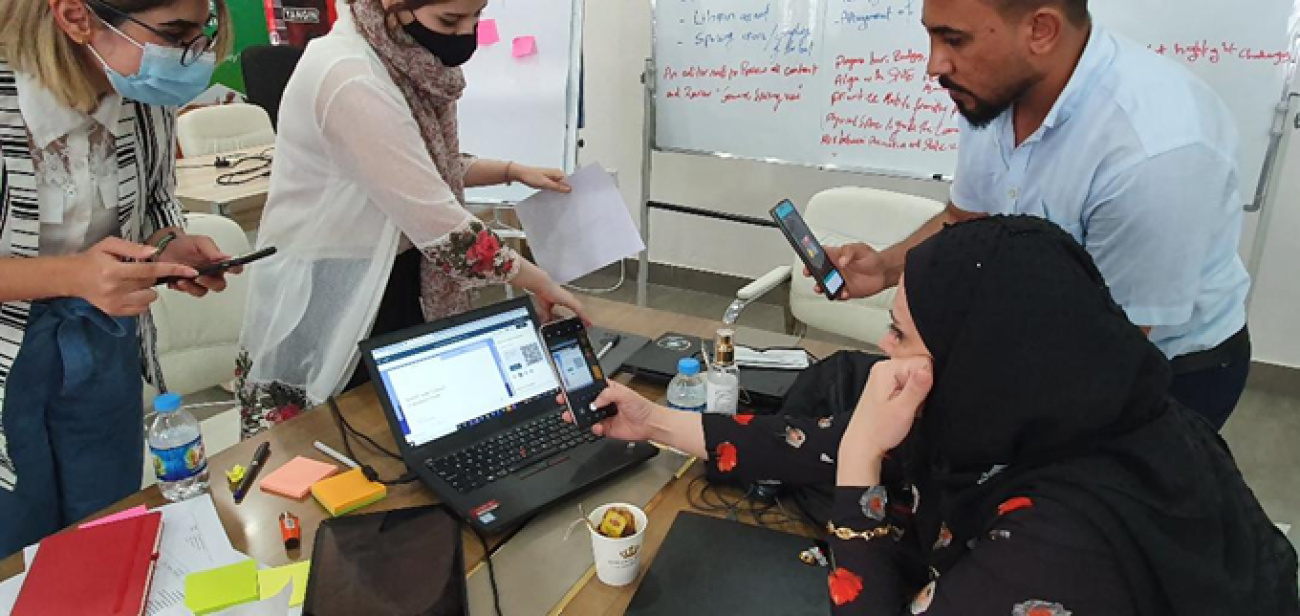 Four people work together on a laptop.