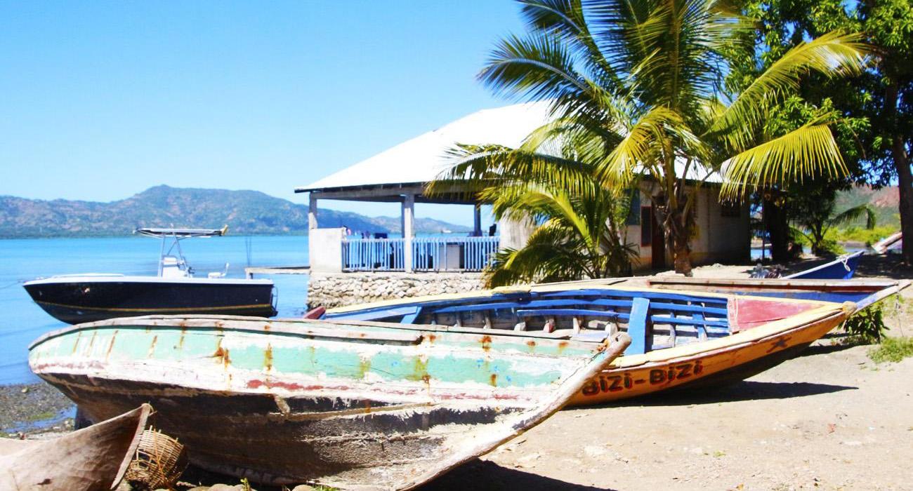 Wooden boats left on a beach next to a business. 