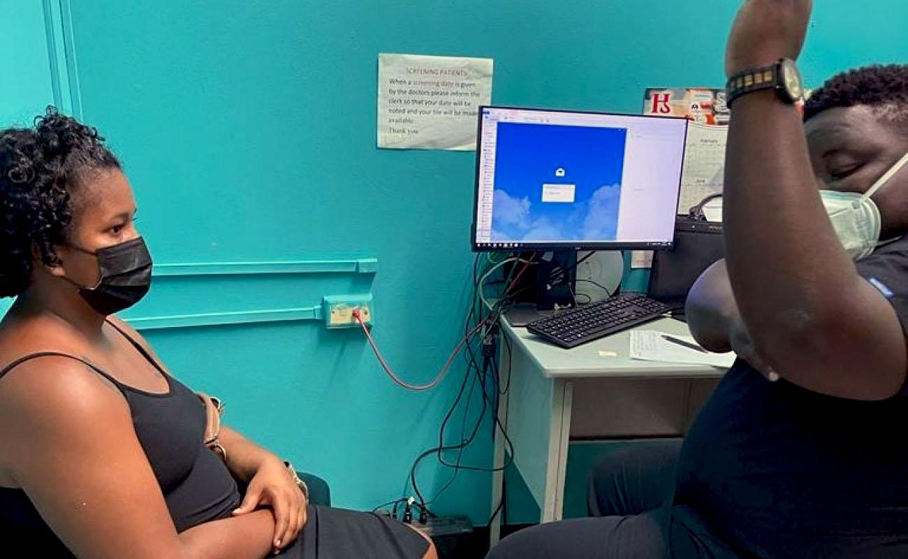 A nurse shows a woman sitting on a chair where her implant will be placed on her arm.