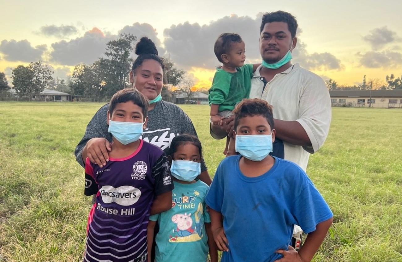 A family of six stand outside during sunset. 