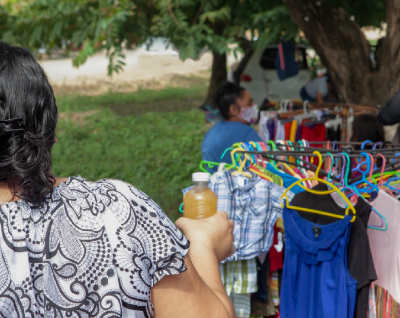 女子背对镜头站立，出售新鲜果汁。
