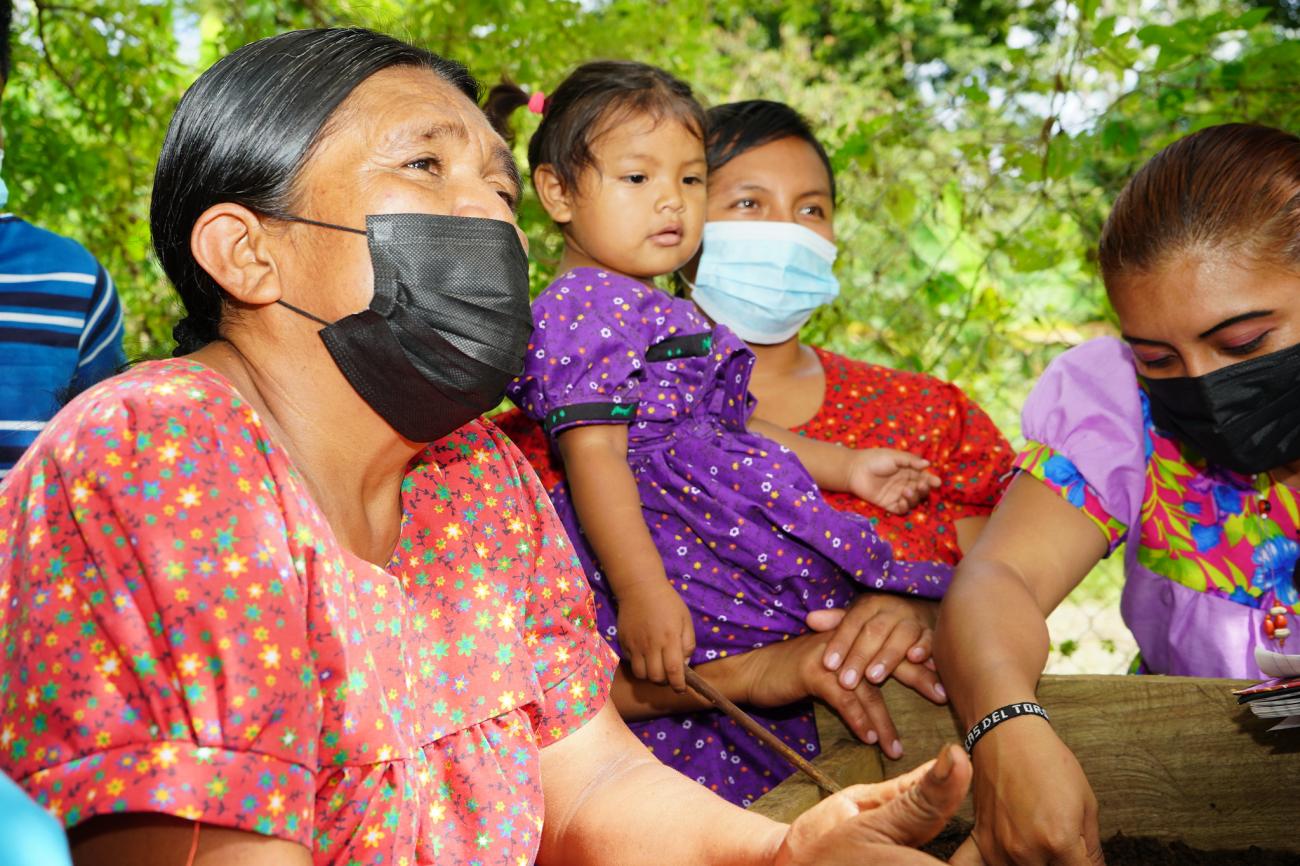 ثلاث نساء من الشعوب الأصلية وفتاة صغيرة في حديقتهم المشتركة.