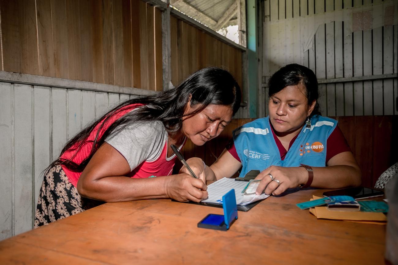 Dos mujeres sentadas a una mesa y concentradas en lo que están escribiendo.