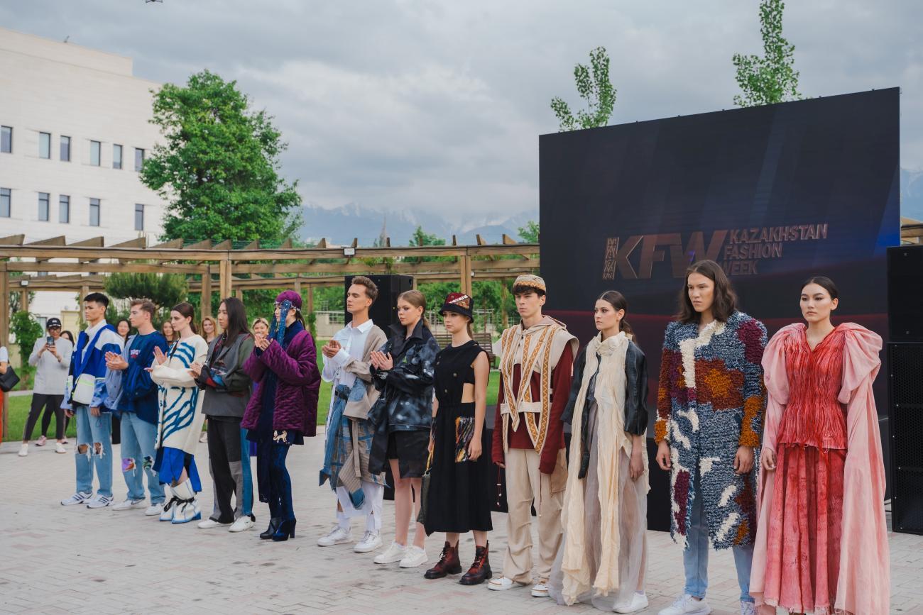 A line of people in fashionable colourful clothes standing against a black and green background