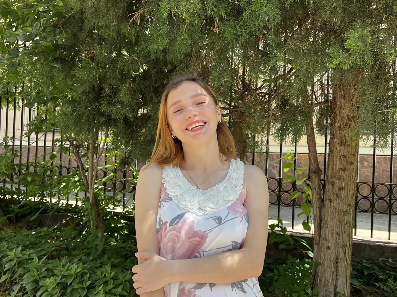 A woman in a white shirt and blonde hair smiles to the camera