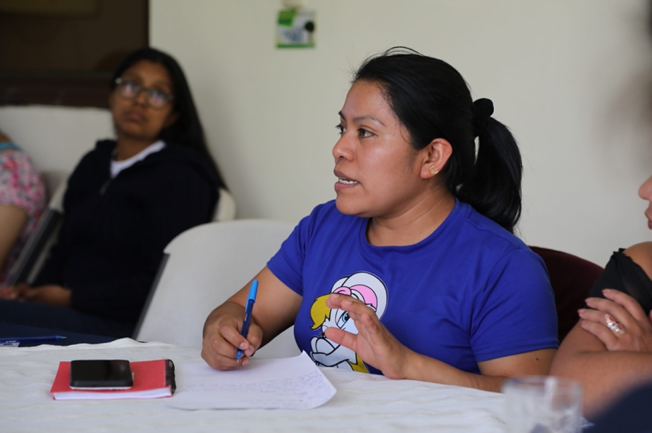 La foto muestra a Floridalma Bocel Raxtún sentada en una mesa hablando en una reunión. Flory está participando en las sesiones de capacitación del programa conjunto de UNPRPD en Guatemala.