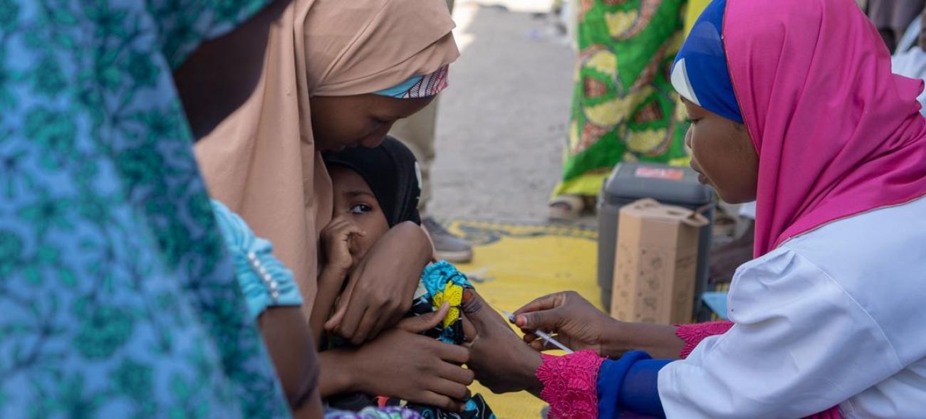 A mother holds her child as a doctor gives her an injection.