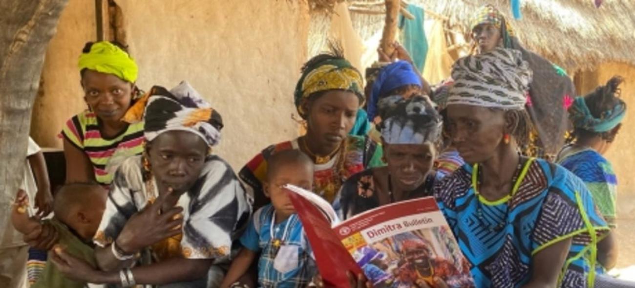 Группа женщин и детей изучает учебник Димитра