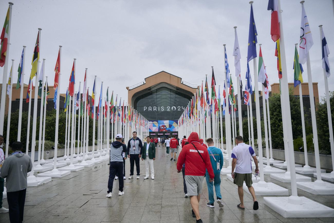 A group of people walk through a row of flags at the Olympics