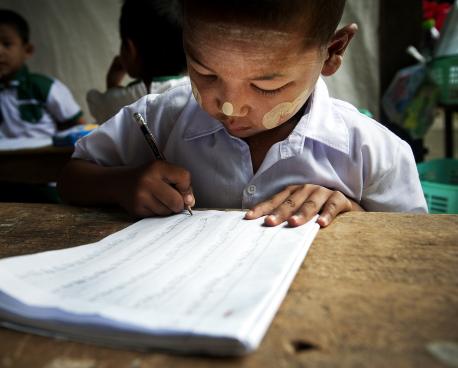 Leave No One Behind section banner shows a child practices his writing during a kindergarten class in Tachilek, Myanmar.
