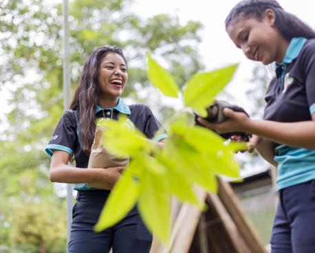 Two girls standing next to green plant