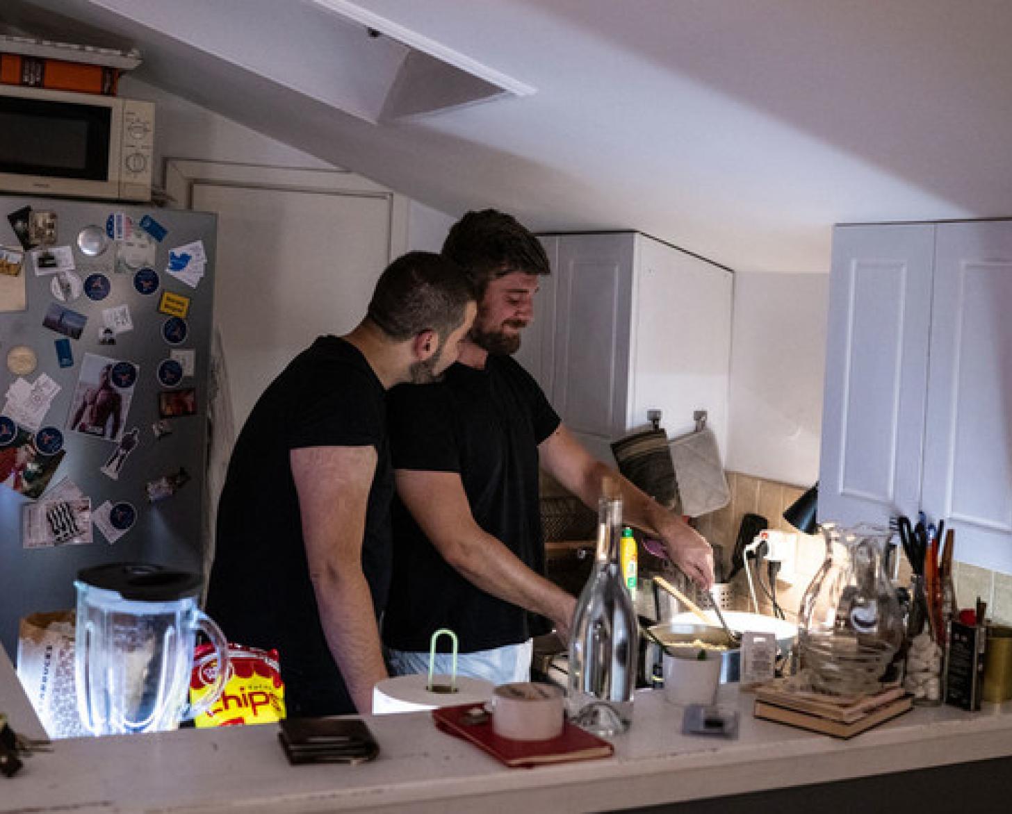 Two men are pictured in their kitchen preparing a meal together