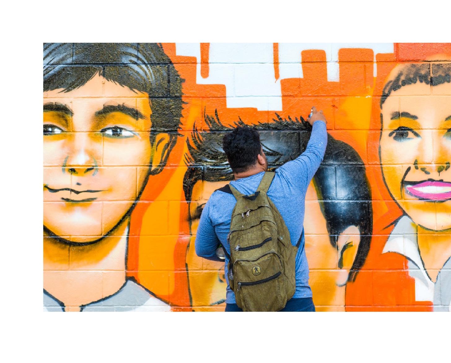 Three images: The first shows a young woman painting the Spotlight Initiative logo against a white coloured brick wall, the second a young man painting a mural of youth, and the last shows children, youth and community members cutting the ceremonial ribbon in front of the painted mural. 