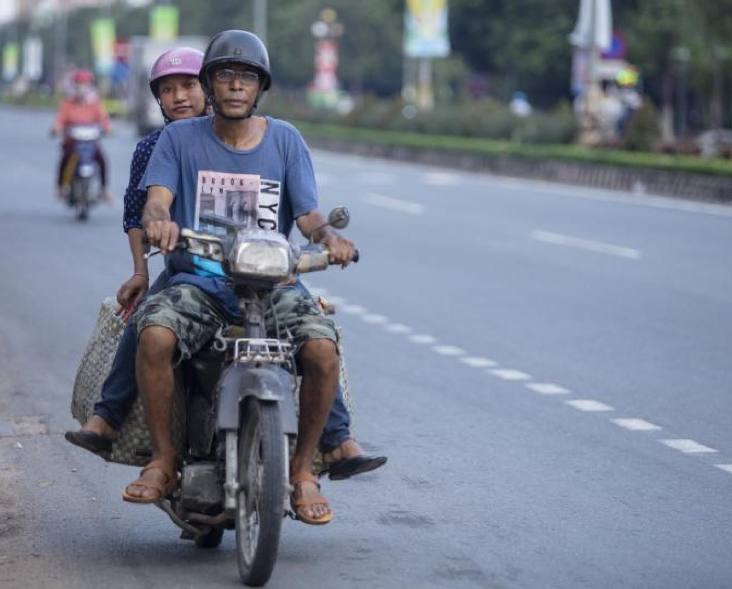 تشاو باو تتمسك برجل بينما يركبان دراجة نارية.