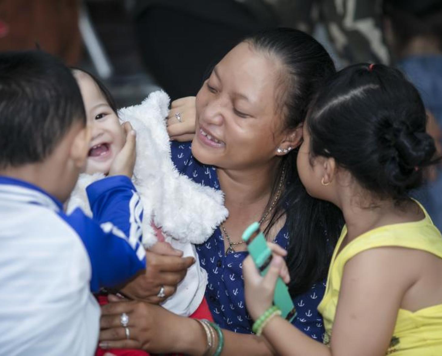 تشاو باو تحمل طفلًا رضيعًا وإلى جانبها صبي وفتاة.