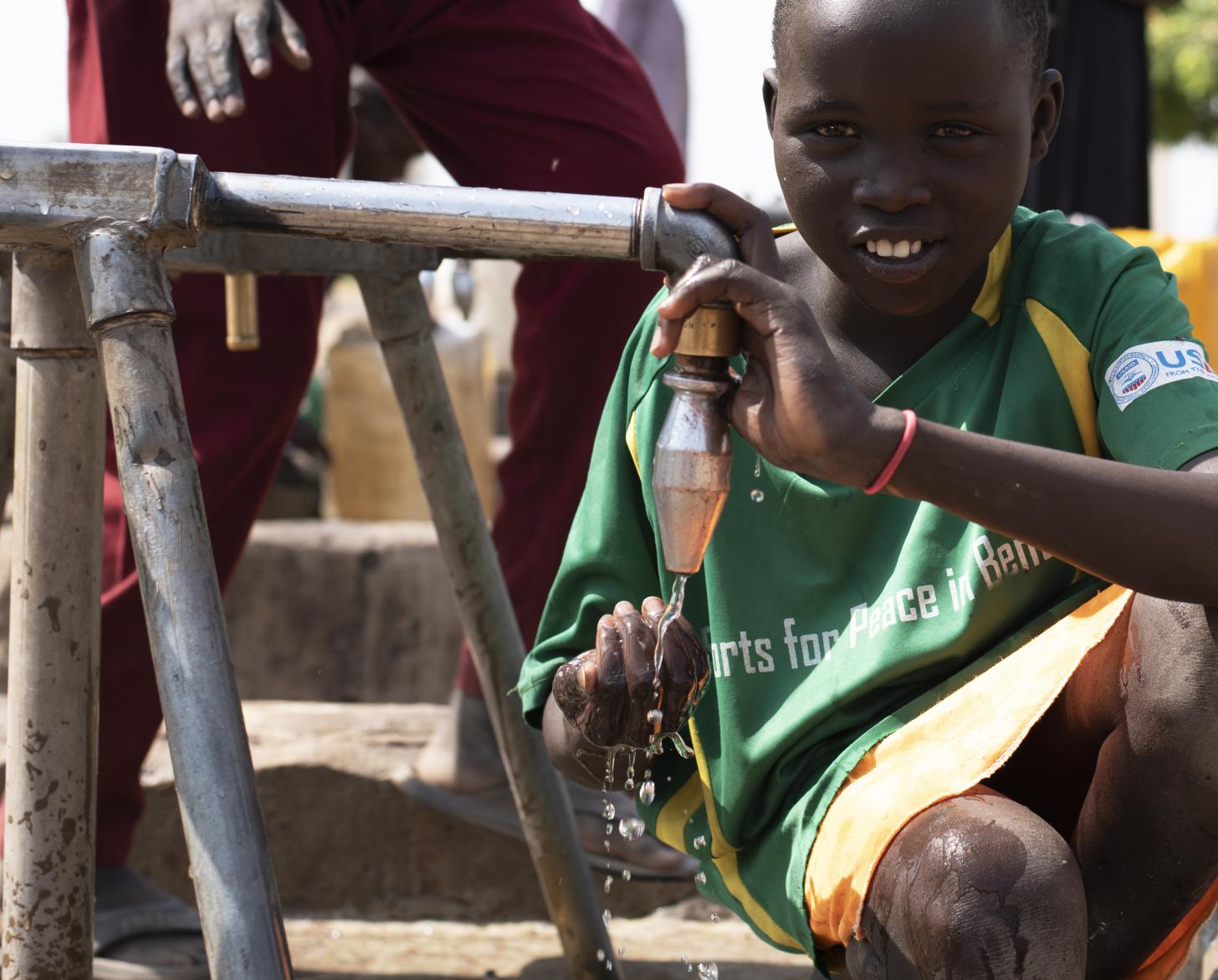 Fuera de la planta de tratamiento de agua en Bentiu, los niños beben de un quiosco de agua suministrado por la planta de tratamiento de agua.
