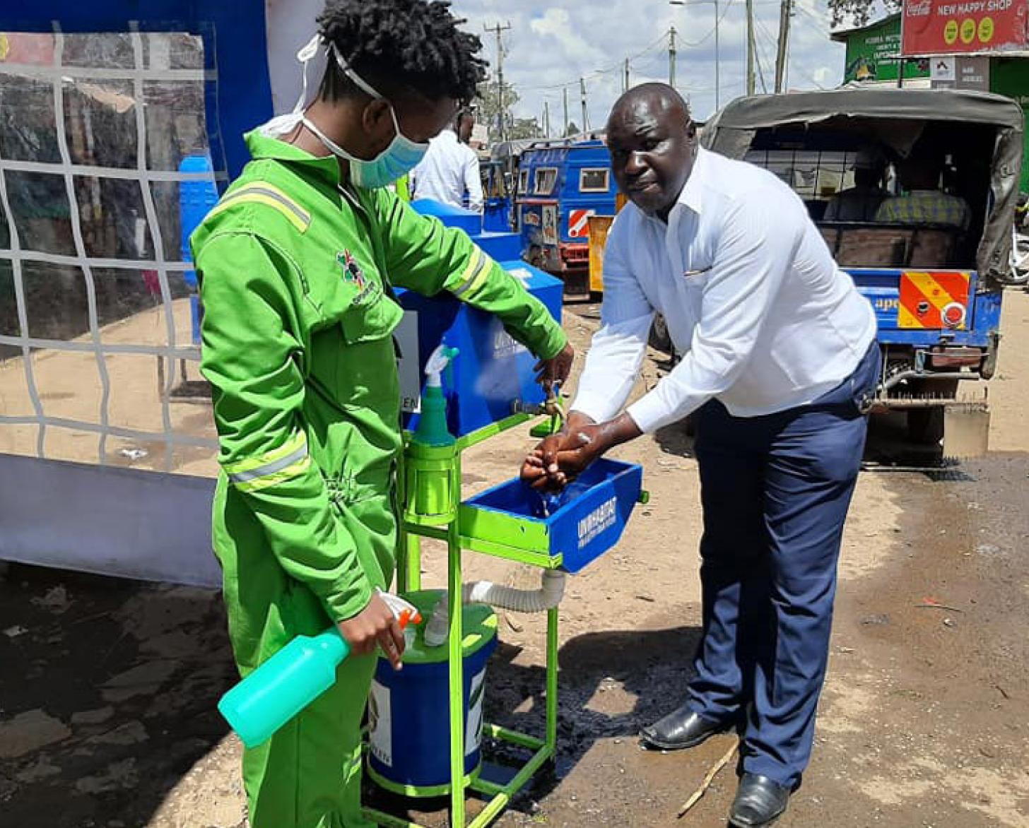 Residents of Nairobi's Kibera informal settlement try out the new UN-Habitat supported handwashing facility to protect against COVID-19.
