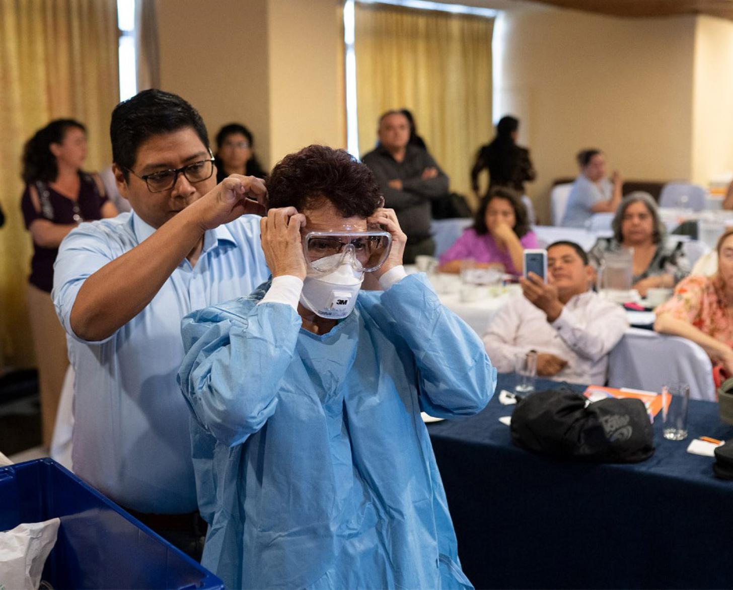 Los hombres demuestran cómo ponerse correctamente el equipo de protección.
