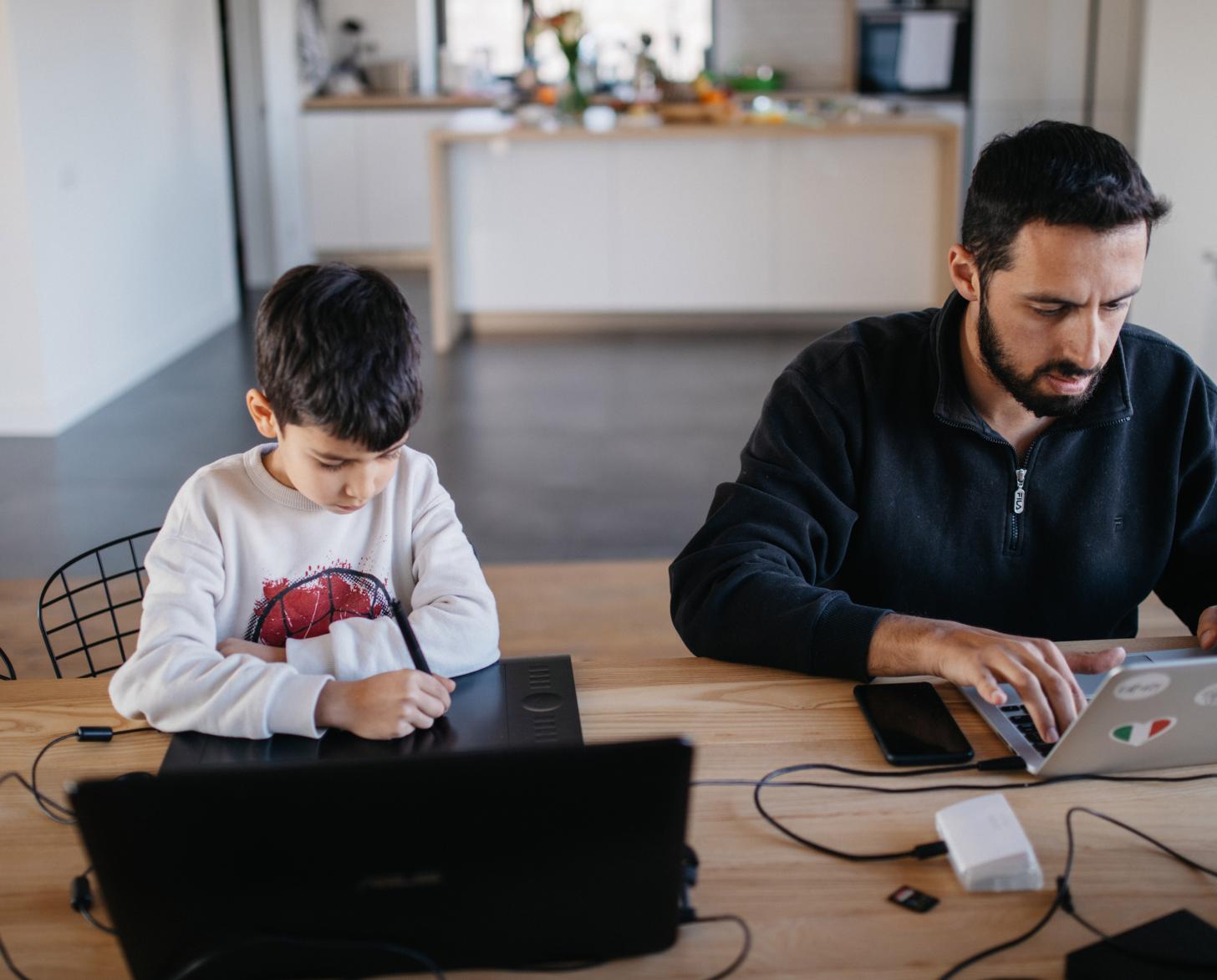 En Ereván (Armenia), Danny, de siete años, se sienta ante un ordenador mientras un adulto a su lado, trabaja de forma remota en su ordenador portátil.